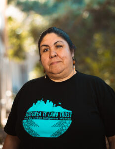 Corrina Gould in black t-shirt with Sogorea Te Land Trust logo