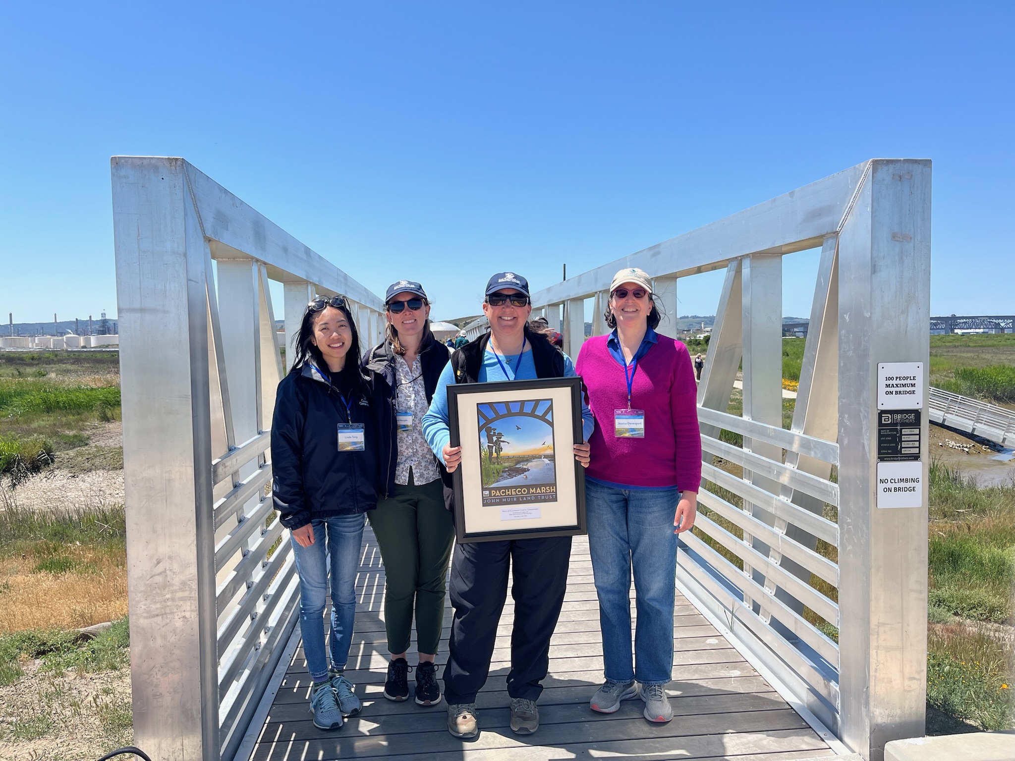 A picture of four people smiling and holding an award in celebration of the opening of the Pacheco Marsh. Karen McDowell, SFEP staff, is pictured. Photo by Taylor Samuelson. 